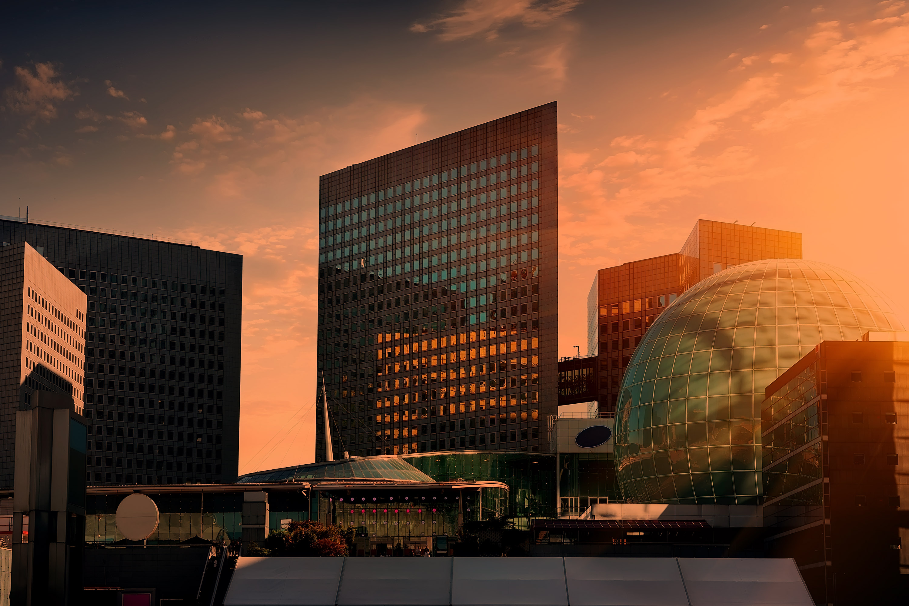 Modern business center Hannover skyline at sunset, showcasing Europe's leading business center in Europe with iconic high-rises, glass dome, and vibrant orange sky—perfect for business center Hannover market entry.